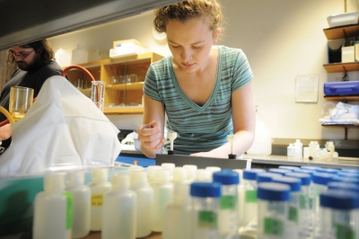 A student records findings among rows of water samples.